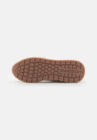 Brown rubber shoe sole with a textured pattern of circular and oval grips, marked with the brand "Gioseppo" indented on the side.