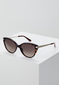 Ochelari de soare tip cat-eye cu un model de broască țestoasă, lentile cu gradient întunecat și accente metalice pe brațe. Rame din plastic neted.