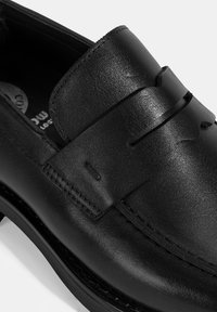 Schwarze Lederloafer mit glatter Oberfläche, dekorativer Naht und rundem Zehenbereich. Beinhaltet ein vorderes Riemen-Highlight mit Aussparung.
