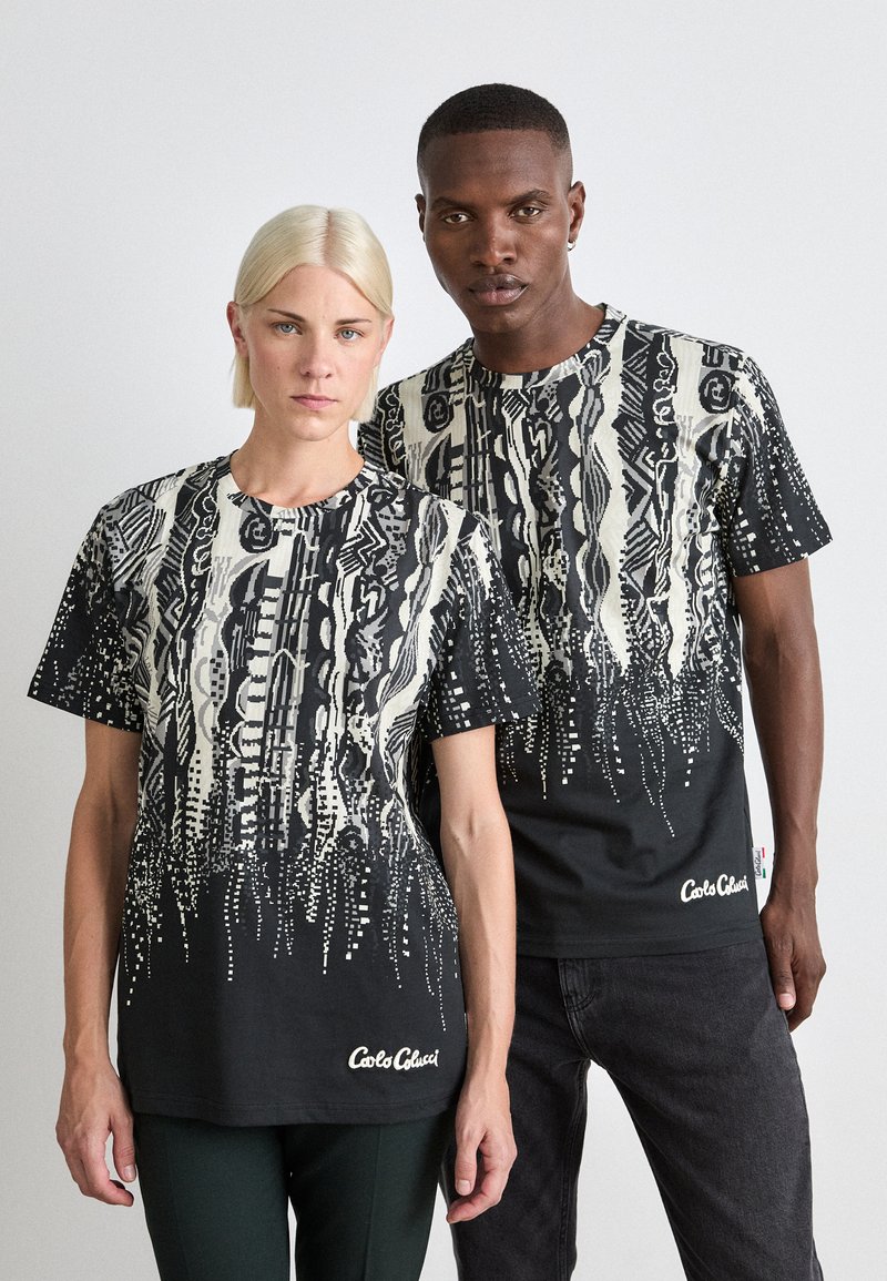 Zwarte T-shirts met korte mouwen, voorzien van witte abstracte patronen en gestippelde ontwerpen. Heeft een ronde halslijn en een logo aan de onderrand.