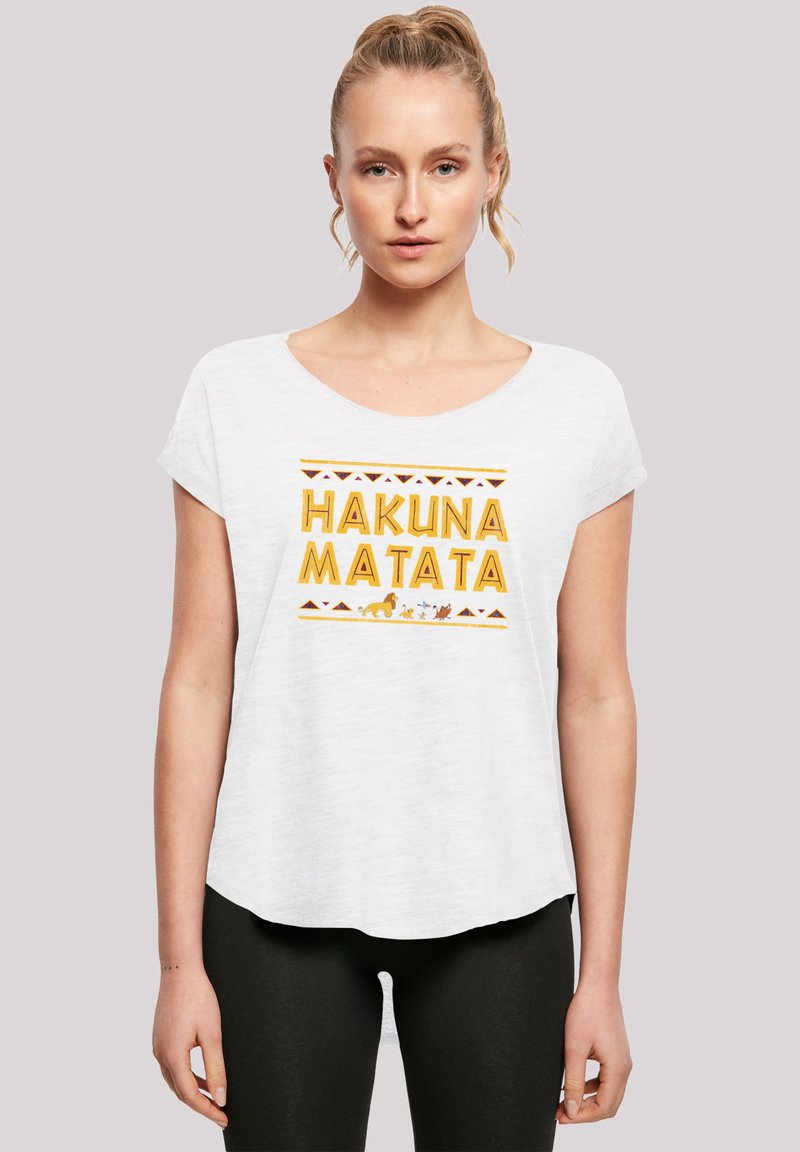 Balts īsajām piedurknēm T-krekls ar dzeltenu uzrakstu "HAKUNA MATATA", zem kura ir ģeometriska raksta un dzīvnieku grafika.