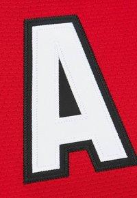 Large white letter "A" with black outline stitched onto red textured fabric background.