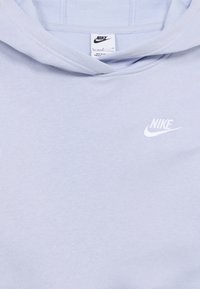 Ανοιχτό μπλε φούτερ με κουκούλα Nike από απαλό, πλεκτό ύφασμα. Διαθέτει μπροστινή τσέπη τύπου καγκουρό και λευκό λογότυπο στην αριστερή πλευρά του στήθους.