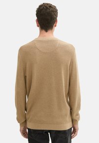 Hellbrauner gestrickter Pullover mit langen Ärmeln, gerippten Bündchen und Saum. Strukturierter Stoff mit lockerer Passform und rundem Halsausschnitt.