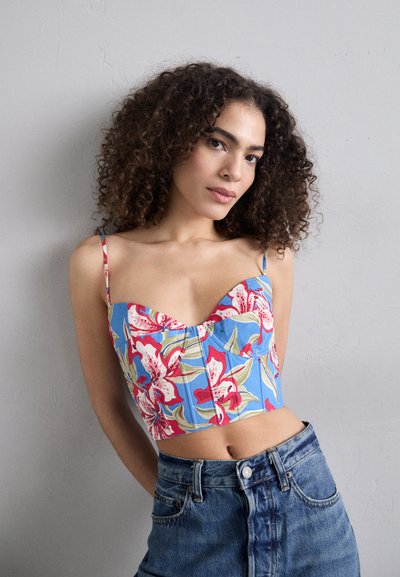 Blomstrete croptopp i blå med rosa og grønne mønstre, med hjerteformet utringning og justerbare stropper, parret med høyt midjede denimshorts.