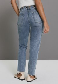 Blugi din denim deschis, cu talie înaltă, cu picior drept, având buzunare la spate și butoane metalice decorative pe talie.