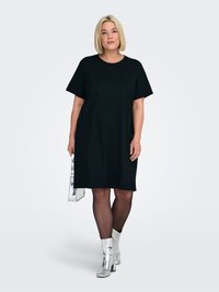 Black t-shirt dress with short sleeves, relaxed fit, knee-length. Paired with metallic silver ankle boots and a small silver handbag.