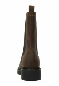Bottine en cuir marron avec des panneaux latéraux en élastique, un onglet au talon et une épaisse semelle en caoutchouc noir. Texture lisse avec des détails minimaux.