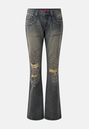 Verkleurde zwarte wijde spijkerbroek met gescheurde knieën, metalen studs en hangende zilveren kettingen op de voorzakken en benen.