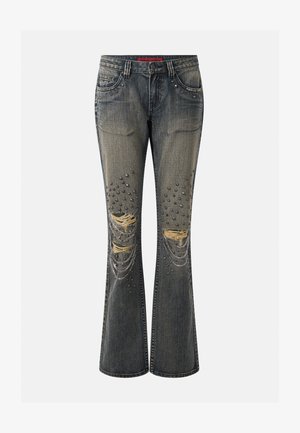 Jean évasé noir délavé avec genoux déchirés, clous métalliques et chaînes argentées suspendues sur les poches avant et les jambes.