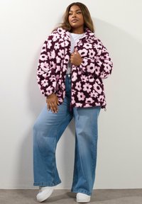 Fioletowa, puszysta kurtka z dużymi różowymi kwiatowymi wzorami, z zamkiem błyskawicznym z przodu i ściągaczem u dołu. Połączona z jasnoniebieskimi spodniami o szerokich nogawkach i białymi trampkami.