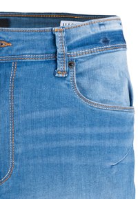 Jeans de mezclilla azul claro con cintura media, costuras naranjas, diseño de cinco bolsillos y un ajuste clásico. Presenta un cierre de botón metálico.