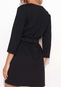 Vestido negro con mangas de tres cuartos, cinturilla elástica y una textura suave, diseñado para realzar la silueta.