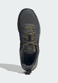 Szare buty sportowe z oddychającą siateczkową cholewką, zielonymi akcentami, płaskimi sznurowadłami i teksturowaną podeszwą. Wzmocniony zapiętek i widoczny detal logo.
