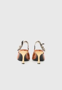 Chaussures slingback en cuir verni marron avec un talon aiguille doré et une sangle logo réglable à l'arrière. Texture lisse et design épuré.