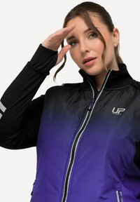 Sportjakke i gradient fra sort til lilla, med høj krave, lynlåslukning, reflekterende detaljer og et logo på brystet.