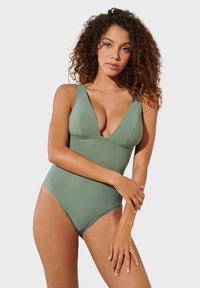 Olive green one-piece swimsuit with a deep V-neck design. Made of smooth fabric, features wide straps and high-cut leg openings.