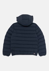 Casaco puffer azul marinho com quilting horizontal, capuz preso, punhos elásticos e um pequeno logótipo circular da marca perto da bainha sobre um fundo branco.