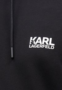 Μαύρη κουκούλα με λευκό λογότυπο "KARL LAGERFELD". Κατασκευασμένη από μείγμα βαμβακιού, με λείο υφή και ρυθμιζόμενο κορδόνι.