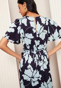 Abito floreale caratterizzato da una base blu navy con grandi motivi floreali azzurri, maniche puff corte, vita arricciata con cordoncino e chiusura con bottoni sul retro.