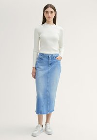 Light blue denim midi skirt with a straight cut, featuring two front pockets and a visible seam detail, paired with a white ribbed long-sleeve top.
