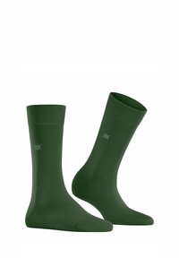 Calzini in cotone verde con parte superiore a coste, texture liscia e dettaglio del logo. Design standard di lunghezza a crew con talloni rinforzati.