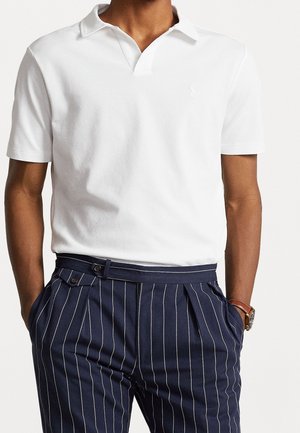 Polo en coton blanc avec une texture douce et un col classique, associé à un pantalon bleu marine à rayures avec une coupe ajustée.