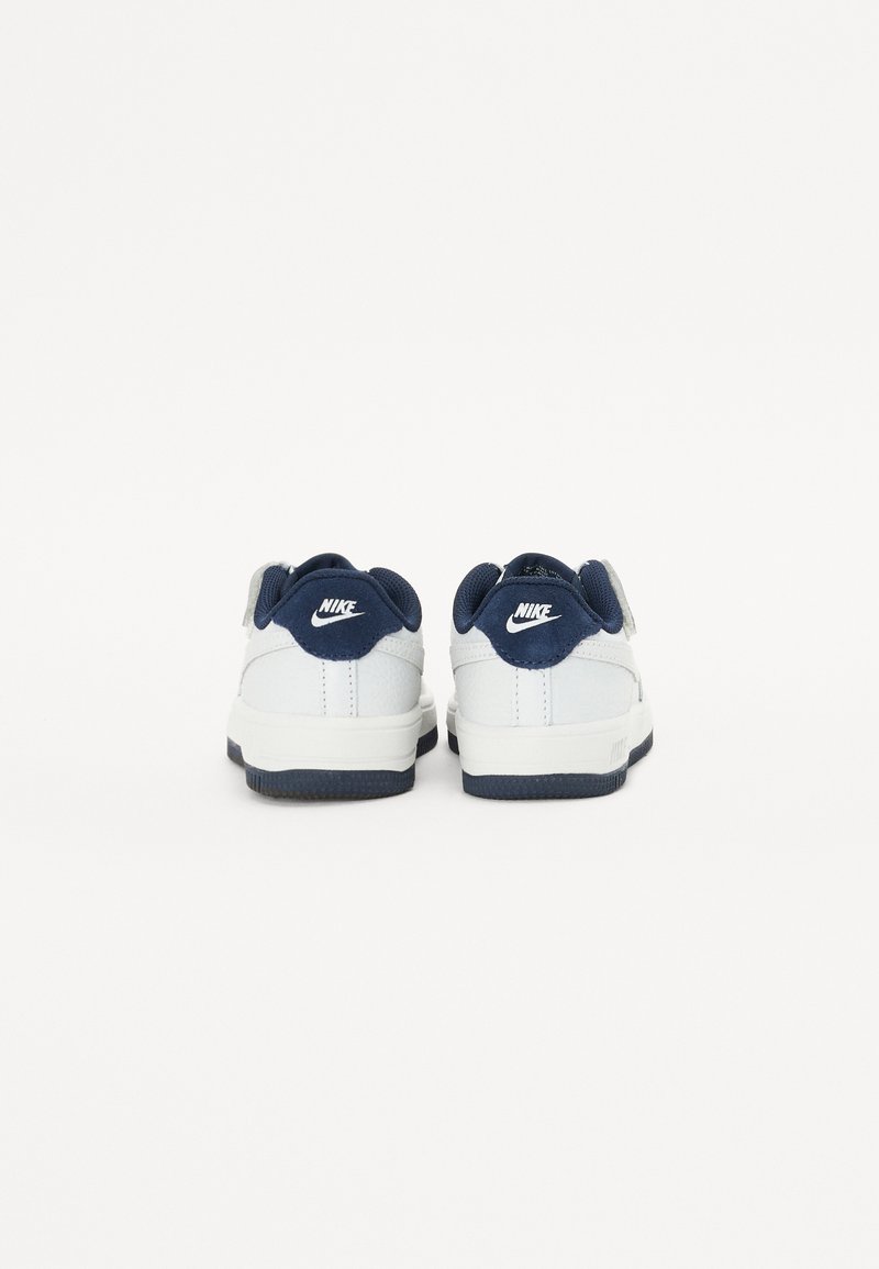 Weiße Sneaker mit navy Akzenten, Obermaterial aus glattem Leder, gepolstertem Kragen und Logo an der Ferse. Gummisohle sorgt für Stabilität und Grip.