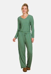 Groene gestreepte lange mouwen top gecombineerd met wijdvallende, groene gestreepte broek. Beide hebben dunne, contrasterende witte strepen en een ontspannen pasvorm.