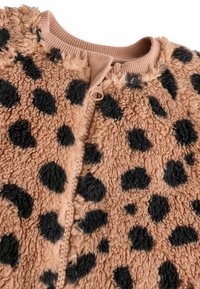 Giacca in pile con stampa leopardata beige e grandi macchie nere. Presenta una finitura testurizzata e una cerniera frontale. Tessuto morbido e colletto a coste.