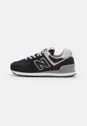 Black and gray New Balance sneaker with white sole and logo, mesh and suede upper, laces tied, side view on white background.