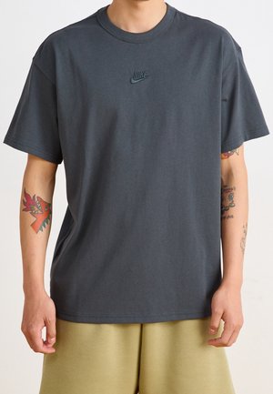 Dark gray cotton t-shirt with short sleeves, featuring an embroidered Nike logo on the chest. The design has a relaxed fit and crew neck.