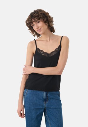 Zwarte cami-top met een kantafwerking langs de halslijn, voorzien van dunne verstelbare bandjes en een relaxed fit, gecombineerd met blauwe jeans.