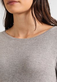 Grauer Strickpullover mit weitem Rundhalsausschnitt und gerippten Details. Weiche Textur mit glattem Finish, geeignet für legere Kleidung.