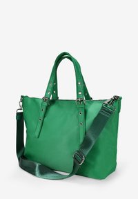 Bolso tote verde hecho de material suave, con asas cortas, correa de hombro ajustable y herrajes plateados decorados con tachuelas.