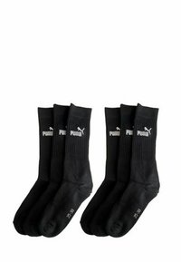 Six black Puma crew socks, ribbed upper with white Puma logo and size markings on the sole, arranged in two groups of three.