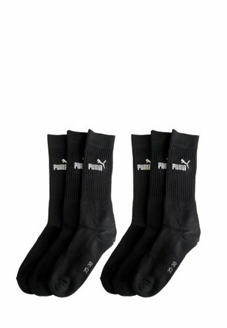 Six black Puma crew socks, ribbed upper with white Puma logo and size markings on the sole, arranged in two groups of three.