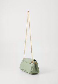 Grüne Lederhandtasche mit runder Form, goldener Kettenriemen und glatter Textur. Verfügt über einen Überschlagverschluss.