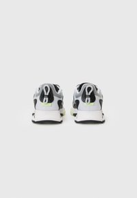 Gray and black sneakers with a white sole and green accents. Features a rounded shape and smooth texture, with a logo on the heel.