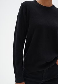 Schwarzer langärmeliger Pullover aus weichem Stoff mit rundem Ausschnitt. Mit gerippten Bündchen und Saum, leicht lockerer Schnitt.