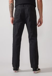 Schwarze Cargo-Hosen aus strapazierfähigem Stoff. Zu den Merkmalen gehören Seitentaschen, ein gerader Schnitt und ein Bund mit Gürtelschlaufen.