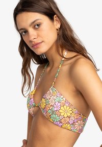 Kleurvolle bikini-top met een bloemenpatroon in geel, roze en groen op een lichtbruine achtergrond, met dunne verstelbare bandjes.