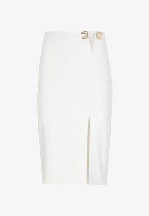Falda lápiz blanca con una abertura frontal y dos acentos metálicos geométricos dorados cerca de la cintura.