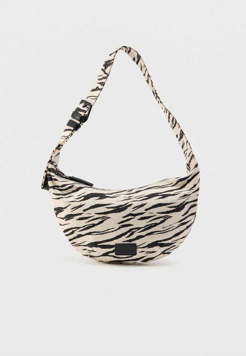 Τσάντα hobo σε μπεζ ύφασμα με μαύρες ρίγες ζέβρας, με κυρτό σχήμα, ρυθμιζόμενο λουράκι και κλείσιμο με φερμουάρ, συνοδευόμενη από μικρό λογότυπο.