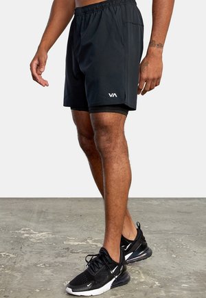Black athletic shorts made of lightweight fabric, featuring an elastic waistband, side pockets, and a white logo on the lower leg.