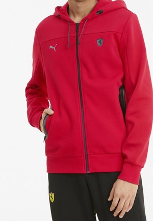 Rød zip-up hoodie lavet af blødt stof, med et Puma-logo på brystet, Ferrari-emblemet, hætte med snore og sidelommer.