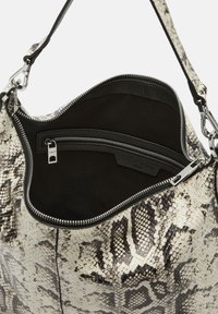Sac à main imprimé serpent avec un intérieur noir, comprenant un compartiment zippé et des finitions en acier inoxydable. Fabriqué en cuir avec des motifs texturés.