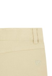 Pantaloni in denim beige con una finitura testurizzata, caratterizzati da una vita cucita, passanti per cintura e un sottile logo di un orso nell'angolo superiore.