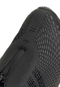 Acercamiento de una zapatilla Adidas negra con parte superior de malla, cierre de cremallera y la marca "Megaride 22" en la zona de la suela.