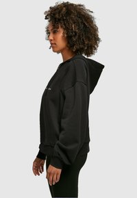 Merchcode WD - STRONG AS A  - Kapucni - black
